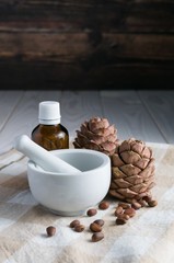 close-up, pine cones with nuts, glass bottle and mortar on a table on a wooden background