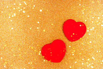 Two red wooden hearts on gold sparkles background.