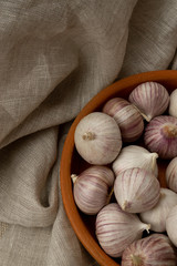 Solo garlic in clay plate on gray fabric, view from above, vertical photo