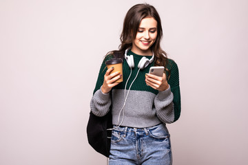Young student woman with backpack and white headset video chatting via mobile phone while standing...