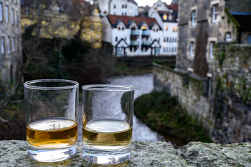 Scotch single malts or blended whisky spirits in glasses with old houses of Edinburgh on background, Scotland, UK