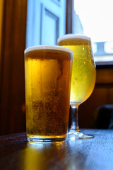 Misty glasses with two pints of cold Scotch ale, amber pale ale, lager draft beer in English pub