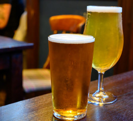 Misty glasses with two pints of cold Scotch ale, amber pale ale, lager draft beer in English pub
