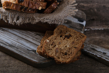 Pieces of rye bread with pieces of dried fruit on a cutting board on a wooden table.