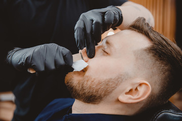 Hair removal with wax from man nose, beauty and care procedure depilation in barbershop