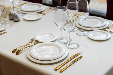 Chic and elegant, gold-plated cutlery and white plates, table setting with empty plates. - Powered by Adobe