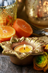Candle holder in the shape of a golden flower, orange and ranunculus