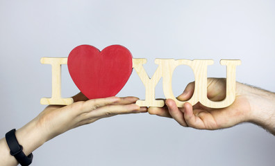 A pair of lovers hold in their hands the inscription "I love you.".The words "I love you" made of wood.