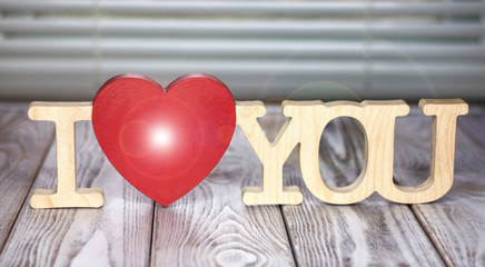 The words "I love you" made of wood..A flash on a red heart.