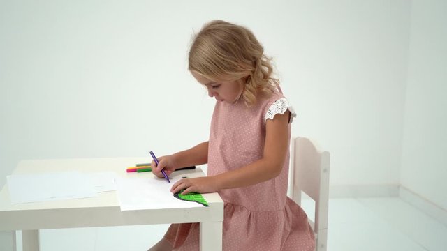 A little girl is drawing at the table.