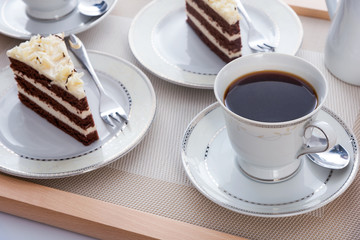 Tasty cocoa cakes with cups of coffee on a wooden tray