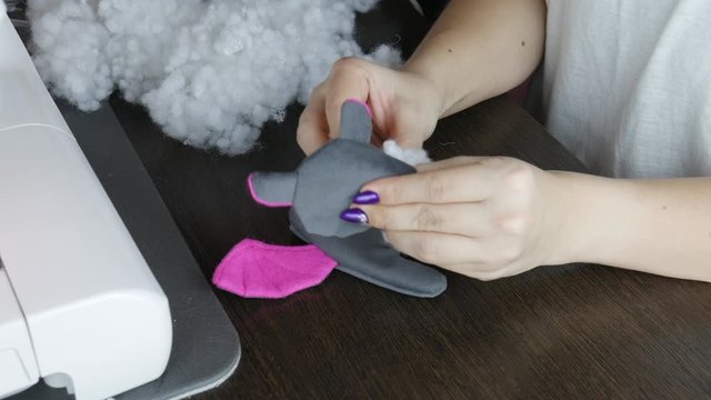 Woman fill handmade textile with white fluffy stuffing for soft toy