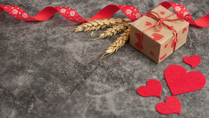 Holiday background for Valentine's Day on a gray cement background with hearts, gifts and a ribbon.