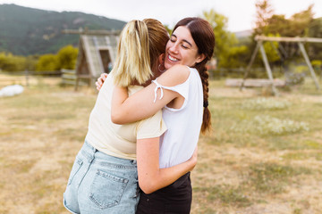 Rear view of girlfriends hugging each other in the countryside. Best friend, love and friendship concept.