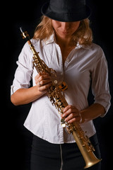 soprano saxophone in the hands of a girl on a black background