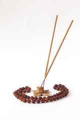 rosary of Rudraksha seeds and incense sticks in a wooden stand isolated on a white background