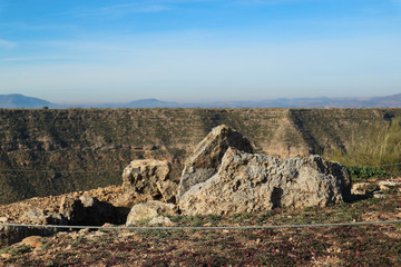 landscape with stones of ancient megalithic burial construction dolmen in Gorafe badlands, Spain and blue sky