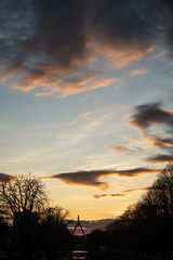 view of tree silhouettes and suspended bridge solhouette under the river and beautiful cloudy sky by sunset