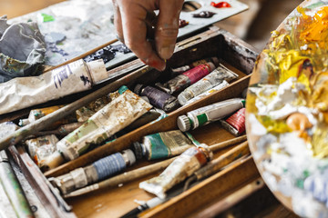 Male painter at art studio indoors choosing color close-up
