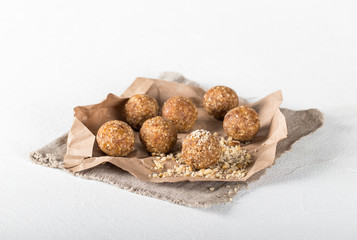 Energy balls made of dried apricots, dates, cashews and almonds on a linen napkin on a light background