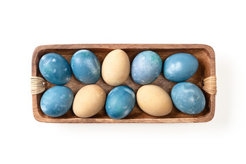 Different easter eggs in wooden bowl isolated on white