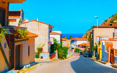 Obraz premium Street Cityscape of car road at Buggerru city at the Mediterranean Sea in South Sardinia in Italy. Sardinian Italian small town in Sardegna. Urban district. Cagliari province. Mixed media.