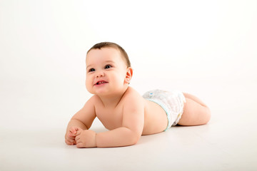 healthy baby brunette boy smiling and looking at the camera, baby in a diaper lying on a white...
