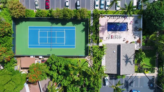 tennis court, parking lot with cars and people in a pool, overhead aerial view moving forward