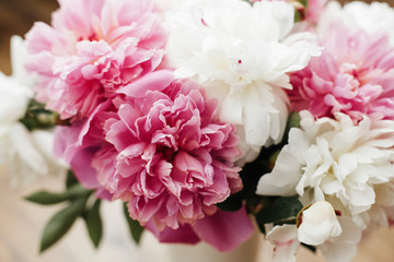 Beautiful peony bouquet in sunny light. Stylish pink  and white peonies on wooden background. Hello...