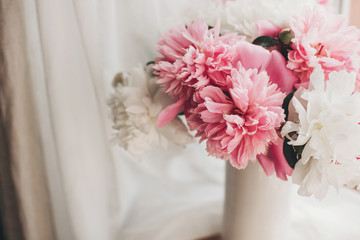 Lovely peony bouquet in sunny light on rustic wooden window sill. Stylish pink and white peonies in vase on wooden background. Hello spring. Happy Mothers day greeting card