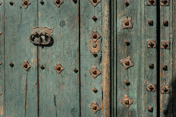 Rusty old knocker on weathered wooden door Greenish deteriorated door detail