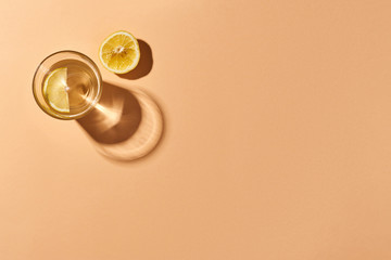 Glass of water with lemon and a slice of lemon isolated on orange. Orange background. Top view.