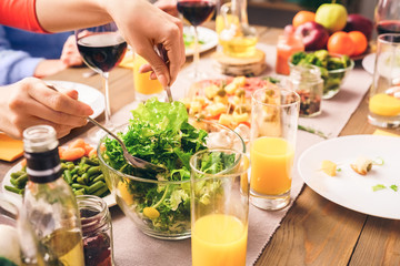 People sitting at home behind table, eating fresh and healthy food