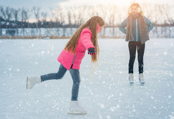 Girl teenager skating with white skates on the ice area in winter day. young Figure skating girl at...