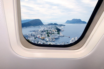 Fototapeta premium beautiful heavenly landscape of blue sky with clouds and views of the earth, cities below behind the porthole of a plane, travel concept