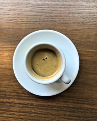White cup of coffee on wood effect table view from above