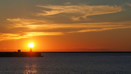 Very beautiful sunset over the pier. Bright orange sun disc.