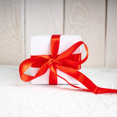 Gift box for Valentine's Day. View of present box package decorated into the white paper and red bow-knot. Flat lay on white background. ..