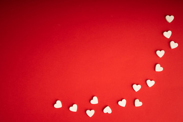 Top view of white wooden hearts on the red paper background. Flat lay for Valentine's Day. Concept of love...