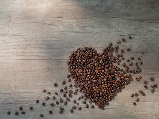 Valentine's Day card - black coffee heart-shaped beans on the surface of a wooden table, with place for text. Top view.