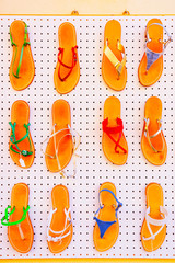 Fototapeta premium Traditional Havaianas Vietnamese flip-flops shoes on dispay at street market in Olbia on Sardinia Island in Italy. Handmade sandals souvenirs. Mixed media.
