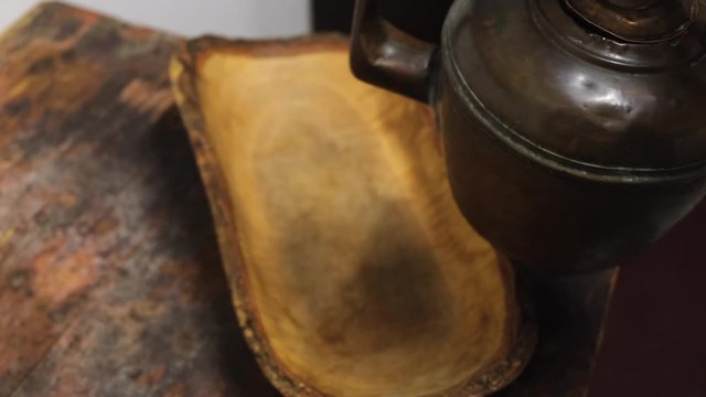 Close-up of man's hand taking an old iron kettle from the wooden board. Concept. Exposition at the Museum