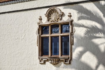 mullioned window in whitewashed building in the sun, with the shadow of a large palm tree