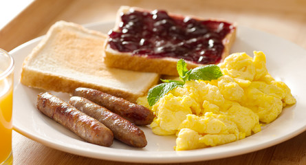 breakfast with scrambled eggs, sausage links and toast.