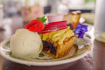 View of apple crumble berry pie cake with vanilla ice cream on top with strawberry.