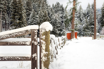 A wooden fence post covered in snow during winter in the rural mountains of North Idaho, USA