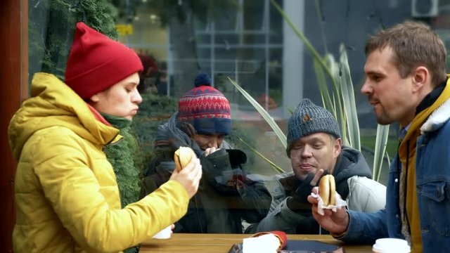 a couple of homeless men and women ask for food from visitors to a street cafe