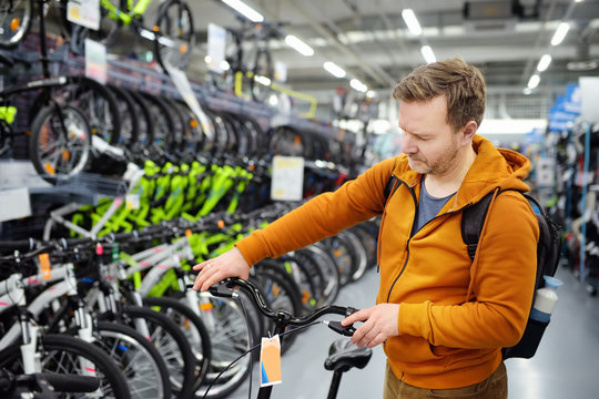 Middle Age Man Choosing Bicycle In Sport Store.