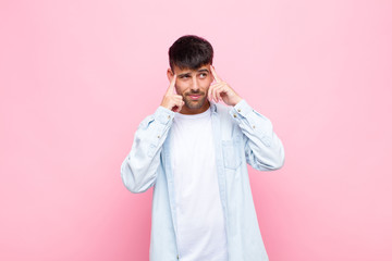 young handsome man looking concentrated and thinking hard on an idea, imagining a solution to a...