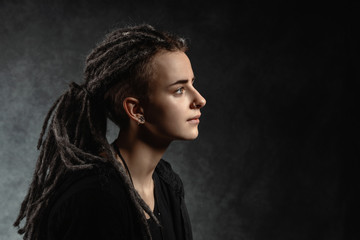 Portrait of a stylish young woman with dreadlocks against dark background